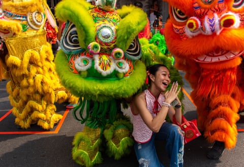 A woman poses with lion dancers in the Chinatown in Bangkok, Thailand.
