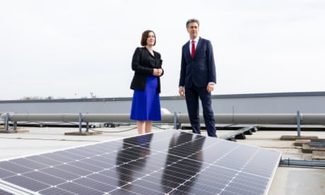 The energy secretary, Ed Miliband, and education secretary, Bridget Phillipson on a school roof next to some large solar panels