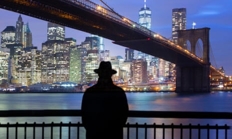 Man standing before Brooklyn bridge and view of lower Manhattan.