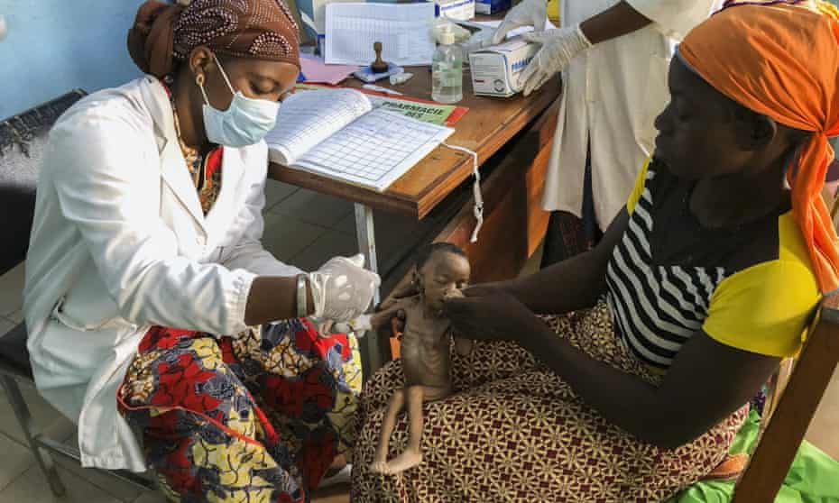 Danssanin Lanizou, 30, holds her month-old baby as a nurse inserts a drip to treat her malnutrition at Houndé hospital in Tuy, Burkina Faso. 