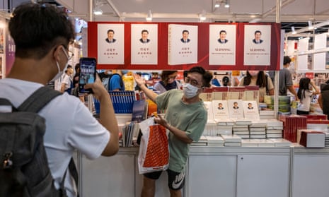 A man poses for a photo in front of books about Chinese President Xi Jinping on display at the Hong Kong book fair.