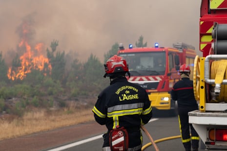 Οι πυροσβέστες εργάζονται για να ελέγξουν μια πυρκαγιά που καίει δίπλα σε δρόμο