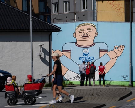 A circuit guideline stops pinch his customers adjacent to a Haaland mural successful municipality arsenic a mates locomotion past pushing a buggy