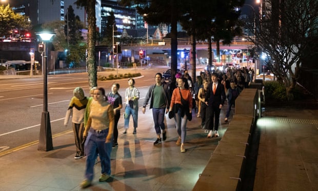 Participants in Nightwalks with Teenagers, a global social art experiment that sees teenagers lead adults on a tour of their city. Teens and participants walk down a city street at night time