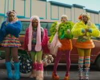 Four women in colourful clothes standing in front of a car