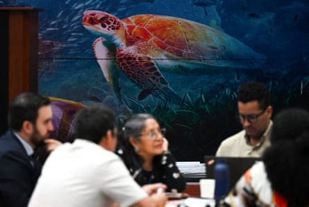 Delegates in a meeting at the conference in front of a colourful mural of a sea turtle