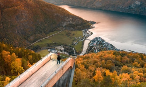 A tourist views Aurlandsfjord from the Stegastein lookout in Norway, at sunset.