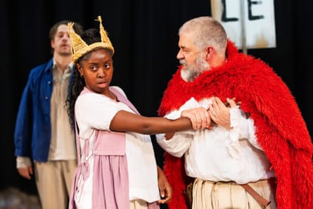 A man in a fluffy red cape is joined on stage by a woman wearing a costume crown.