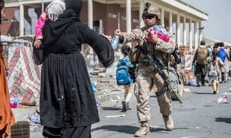 A US marine offers water to a family at Hamid Karzai international airport in Kabul, Afghanistan.