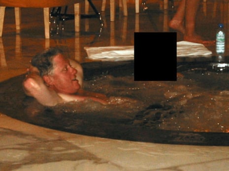 Bill Clinton sits in a jacuzzi. A person next to him has their face redacted from the image.