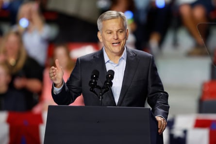 A midle-aged man gestures and speaks into a mic.
