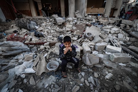A child eats amid the rubble of destroyed buildings following Israeli bombardment in Rafah.