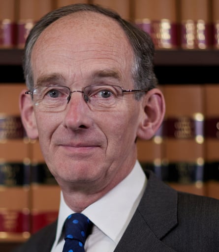 Sir Andrew McFarlane, with wire-framed glasses and in a shirt, tie and jacket, in front of a shelf of law books