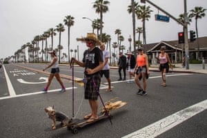 Mike Bennett wears a Patriot face mask while skateboarding with his dog in Huntington Beach, California