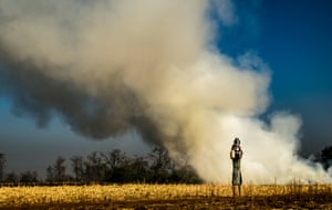 Water girlA young girl carrying metal pitchers on her head pauses as a crop field burns in Maharashtra, India. Women travel far to fetch water from a well located outside the village.