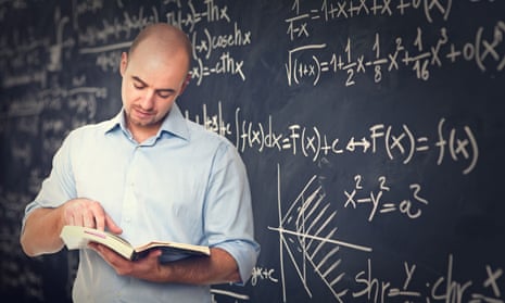 teacher reading a book by a blackboard
