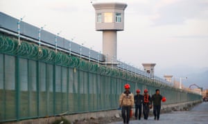 Workers walk by the perimeter fence of what is officially known as a vocational skills education centre in Dabancheng in Xinjiang.