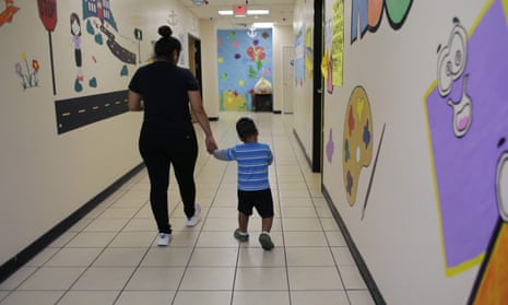A young migrant boy walks with a Comprehensive Health Services caregiver at a ‘tender-age’ facility for babies, children and teens, in San Benito, Texas.