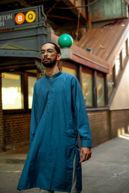 A man wearing a long blue kurta walking outside a New York subway station