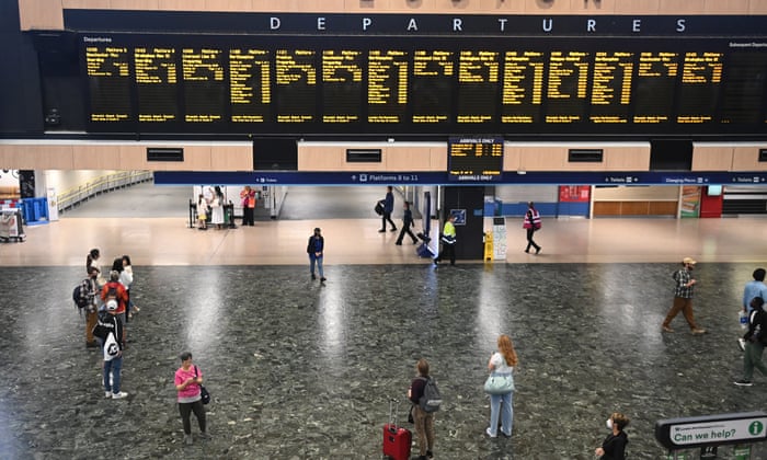 Travellers view an information board at Euston station in London.