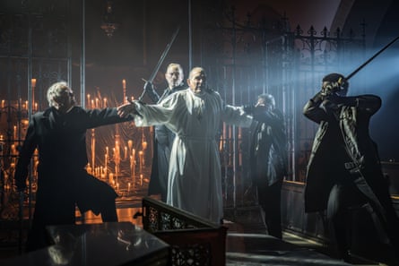 David Suchet as a robed figure spreads his arms between armed men with raised swords