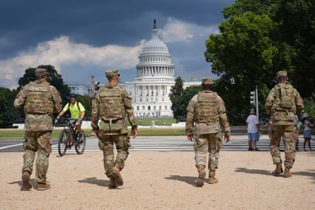 four men in military uniform walk with the uS capitol in the background