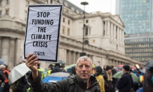 An Extinction Rebellion protester holds a placard saying 'Stop funding the climate crisis' outside the Bank of England on Monday 14 October.