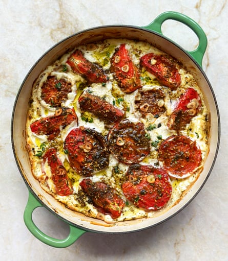 A green pan with tomatoes and a creamy sauce