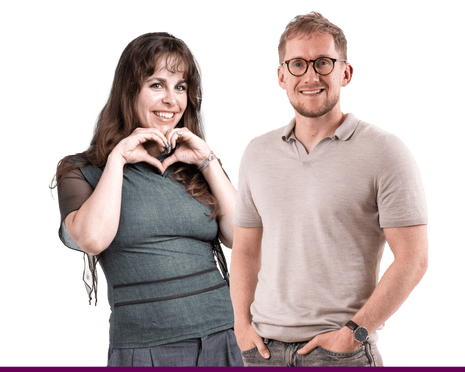 Imogen and Andy. A woman making a heart shape with her hands stands beside a smiling man in glasses