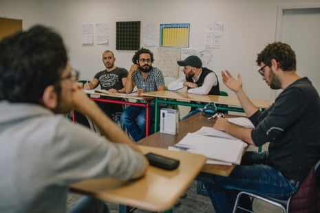 Somar sitting with adult students at desks.