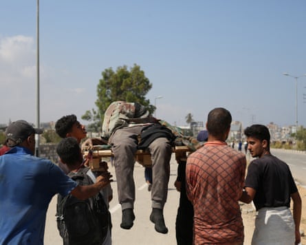 Palestinians carry a victim who was seeking food at a distribution point run by the GHF.