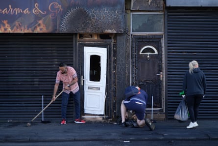 Restaurant owner Luqman Khan and others clear debris from the street outside his restaurant in Middlesbrough the day after the rioting.