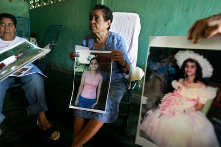 Older women hold photos of a young woman