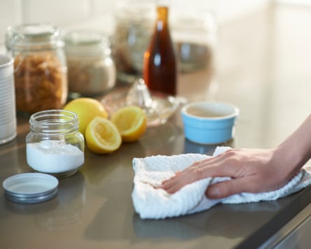A woman cleaning a kitchen worktop with natural cleaning products made from lemon, bicarbonate of soda and vinegar.