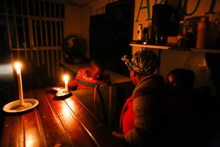 A woman runs her takeaway restaurant by candlelight during a scheduled power outage in the impoverished neighbourhood of Masiphumelele, Cape Town.