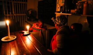 A woman runs her takeaway restaurant by candlelight during a scheduled power outage in the impoverished neighbourhood of Masiphumelele, Cape Town