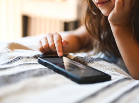 Smiling child using smartphone on bed at home
