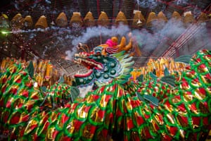 Dancers dressed as a big green and red dragon with smoke pouring from its mouth