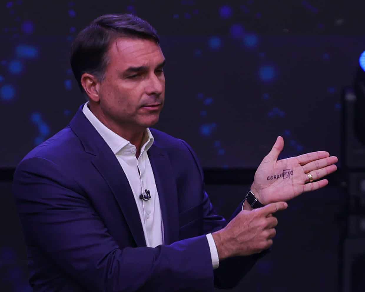 Flávio Bolsonaro gestures while showing writing on his palm during a televised debate