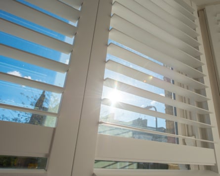 A window with shutters with bright sunlight outside.