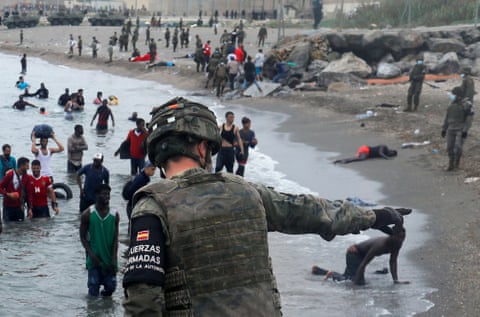 A Spanish legionnaire directs people who have swum across the border from Morocco to the Spanish enclave of Ceuta in May 2021.