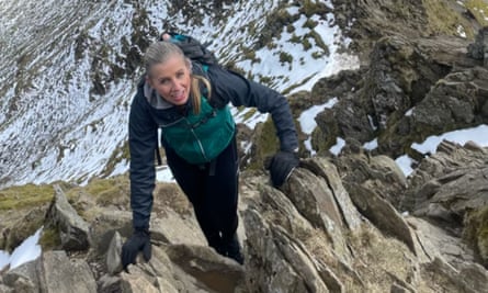 Joanne Noton, 43: she is pictured climbing through rocks in a mountainous landscape, with snow on the peak behind her. She is wearing a green anorak with black sleeves, black trousers and gloves, and is carrying a rucksack; she has long blond hair tied into a ponytail.