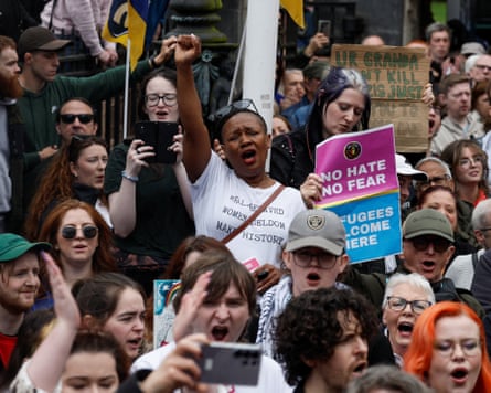 A black woman raises her right arm while others hold anti-racism placards during a rally in Belfast.