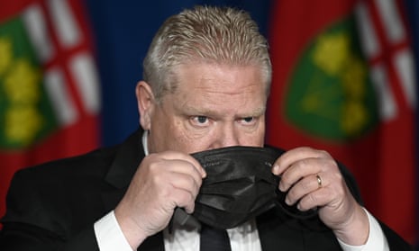 Ontario’s premier, Doug Ford, puts his mask on after announcing the new measures at Queen’s Park in Toronto on Friday.