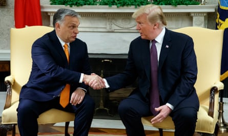 two men in suits shake hands as they sit down