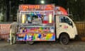 An ice-cream mini-truck open for business, with colourful photographs and illustrations on display