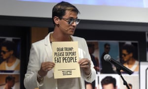 Milo Yiannopoulos holding a 'Deport fat people' sign