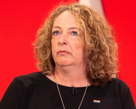 Sara Rowbotham wearing a black top and NHS badge against a red background