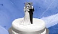 Black-and-white image of wedding cake with bride and groom figurine against a blue background
