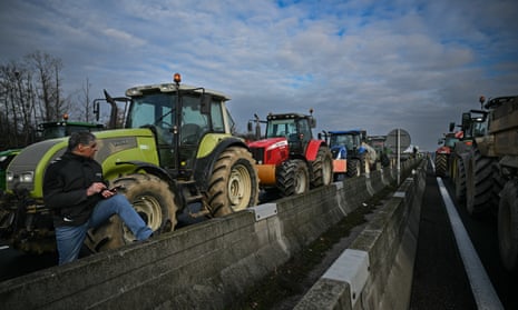 A farmer stands next to a row of tractors blocking the A7 motorway near Arbon in southeastern France.